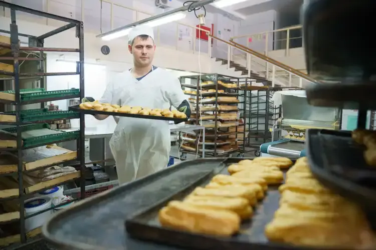 Приготовление торта начинается с выпечки бисквита. Илья Табаев укладывает его для отправки в следующий цех. Для любимой жены обязательно сделает меренговый рулет.
