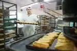 Приготовление торта начинается с выпечки бисквита. Илья Табаев укладывает его для отправки в следующий цех. Для любимой жены обязательно сделает меренговый рулет.