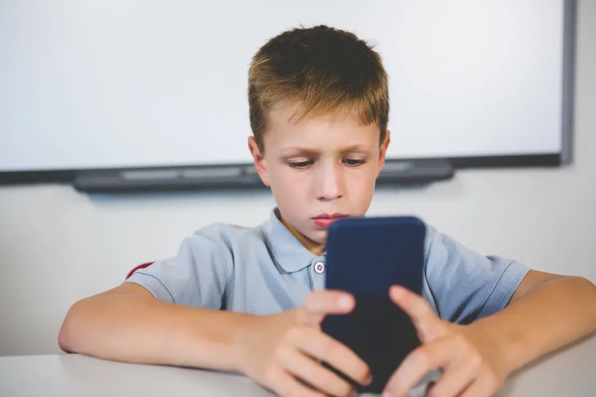12 летний телефон. Школьник сидит в телефоне. Ученик с телефоном. Школьник с телефоном в руках. Школьник с телефоном на уроке.